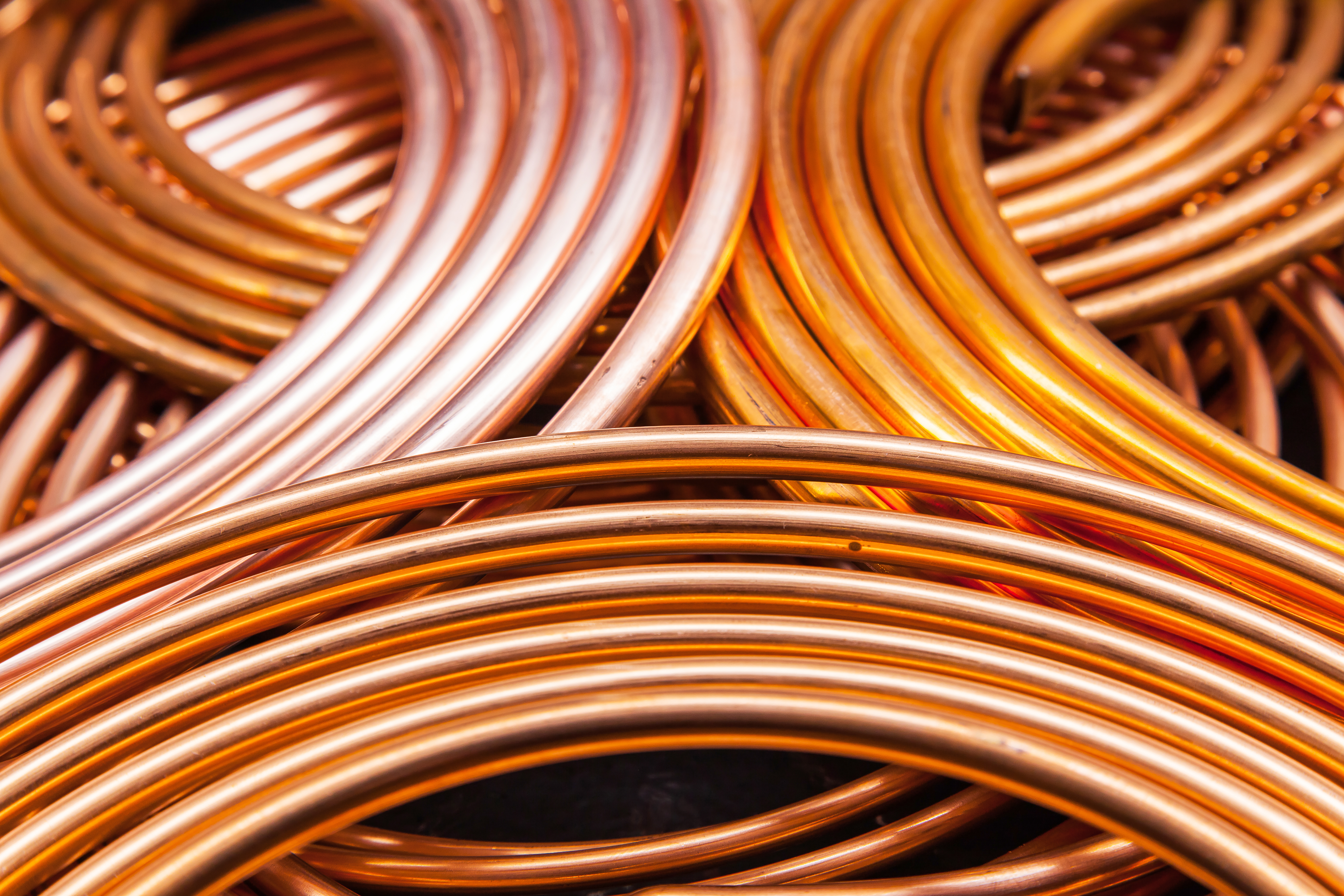 Twisted new copper tubes on a black background.